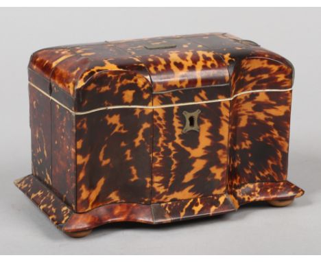 A Victorian tortoiseshell tea caddy. With serpentine front, housing two compartments, with bevelled skirt and raised on butto