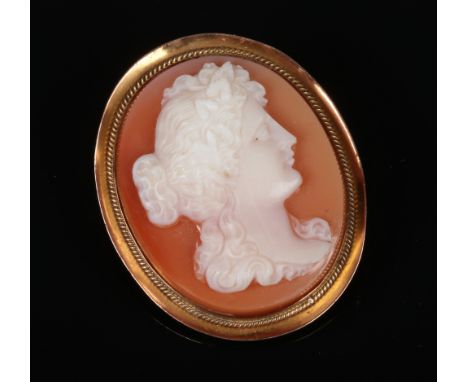 A 9 carat gold mounted oval carved shell cameo brooch. Profile portrait of a maiden, 3.75cm high.  Slight dents to the rim. N
