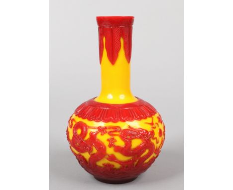 A Chinese Peking glass bottle vase. Red overlay on a yellow ground depicting dragons chasing a flaming pearl under a border o