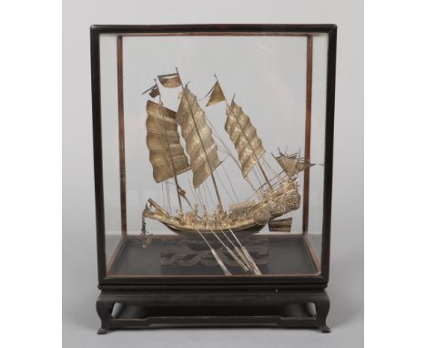 A cased Chinese export silver model of a seven gun war junk. Raised on a carved hardwood wave scroll plinth. the five glass c