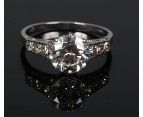 An Art Deco diamond ring stamped plat. With a principle claw set brilliant cut diamond approximately 3.0ct and with three dia