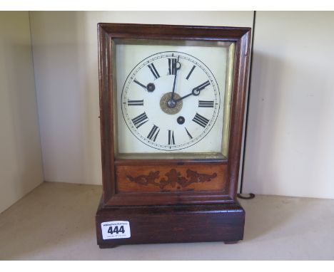 A small wooden cased mantle clock, white enamel dial with Roman numerals to chapter ring, inlaid panel below with key and pen