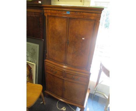 A reproduction burr walnut veneered cabinet having four cupboard doors, two drawers and bracket shaped feet, 60" h x 28"w 