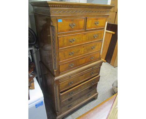 A reproduction walnut veneered chest on chest having a dentil moulded cornice, nine drawers, brushing slide and bracket shape