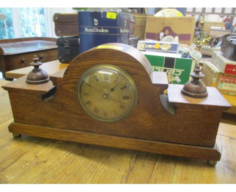 An early 20th century oak mantle clock having a gilt dial and reverse barley twist supports 