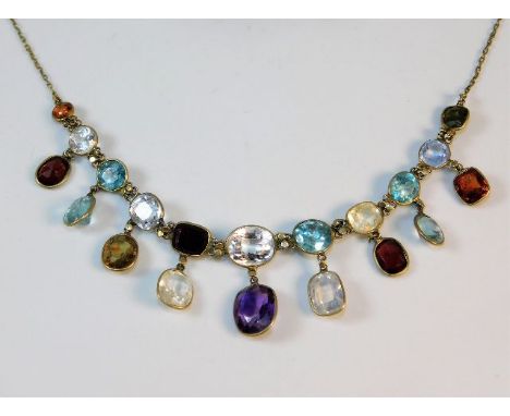 A c.1900 yellow metal necklace set with topaz, white sapphire, zircon, rock crystal, amethyst, aquamarine, garnet &amp; olivi