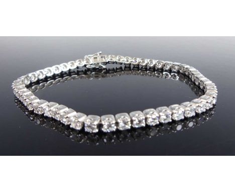 A platinum diamond tennis bracelet, comprising 50 round brilliant cut diamonds in articulated four-claw settings, with integr
