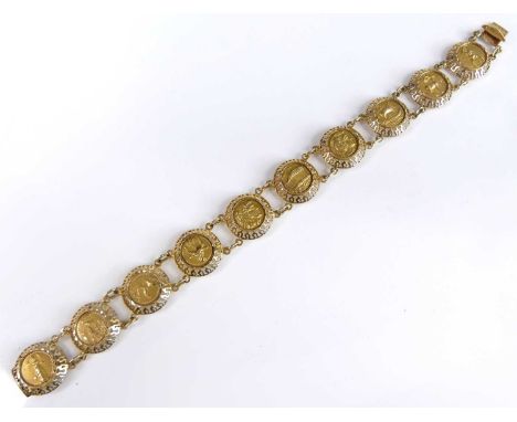 An Egyptian Revival yellow metal disc bracelet, each decorated in relief with Egyptian symbols, stamped 585, and tests as app