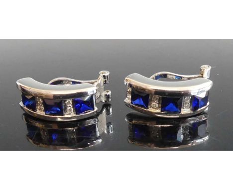 A pair of white metal sapphire and diamond hinged half-hoop earrings, each comprising three French cut sapphires alternating 