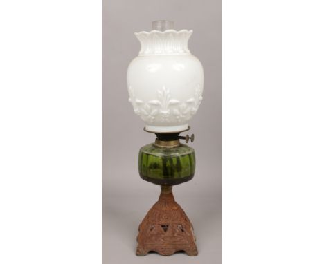 A cast iron base oil lamp with green glass font and milchglas shade. 