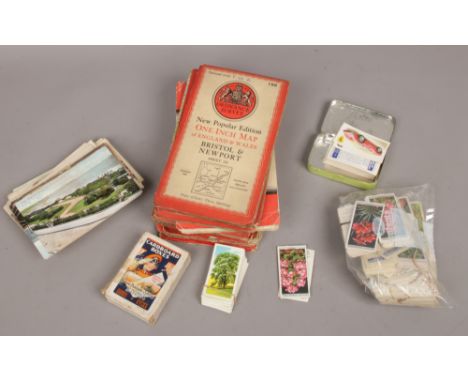 A collection of loose tea cards, playing cards, postcards and ordnance survey maps. 