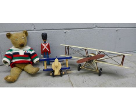 A vintage Teddy bear, a tin-plate model of a bi-plane and two wooden toys 