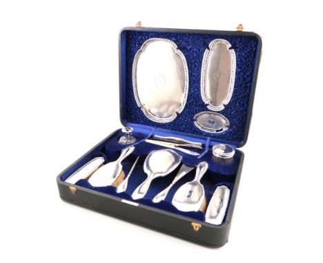 λA cased silver dressing table set, by Walker and Hall, Birmingham 1912, engine-turned decoration, initialled, the trays with