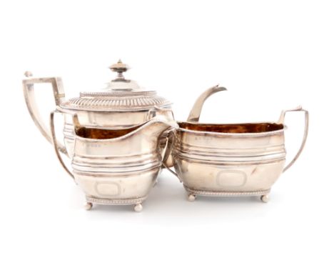 λA three-piece George III silver tea set, by Urquhart and Hart, London 1807 and 1808, oblong form, gadroon border, scroll han