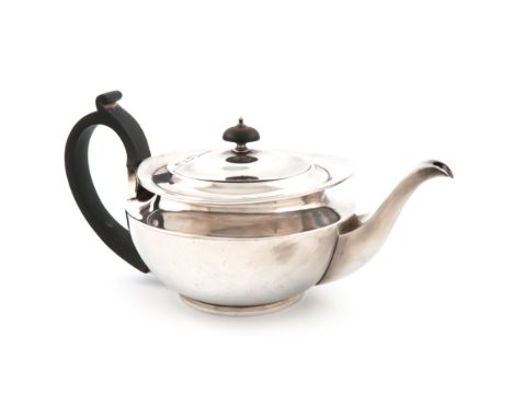 A silver teapot, by D and J Wellby, London 1911, circular cape form, scroll handle, flush-hinged cover, with a knop finial, o