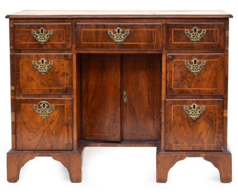 A Georgian walnut and featherbanded kneehole desk, the top with re-rentrant corners above three frieze drawers and two drawer