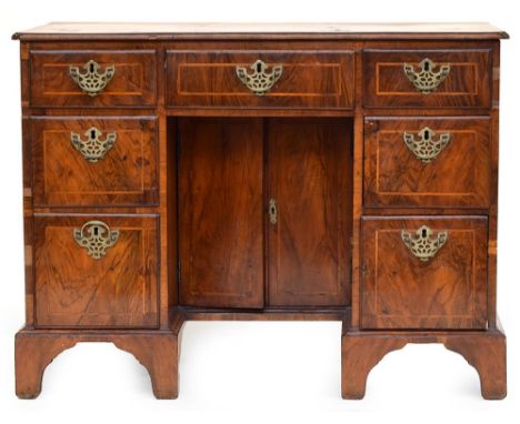 A Georgian walnut and featherbanded kneehole desk, the top with re-rentrant corners above three frieze drawers and two drawer