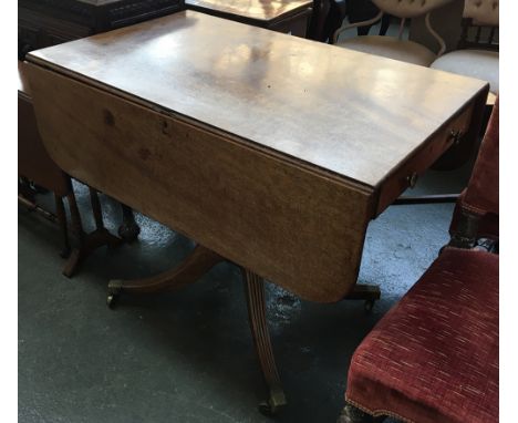 A light mahogany drop leaf table with end drawer, on ring turned column and four swept and reeded legs with brass casters