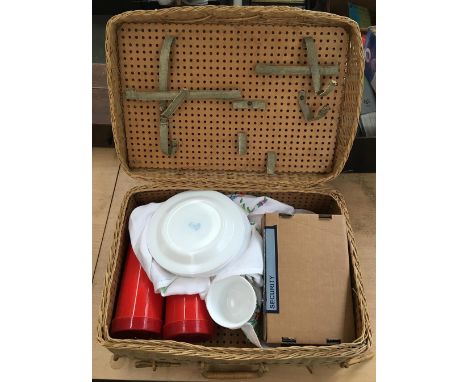 A wicker picnic hamper with thermos, cup, saucers, and plates 