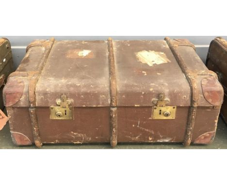 A vintage travel trunk with wood and metal bracing, with vintage travel stickers 