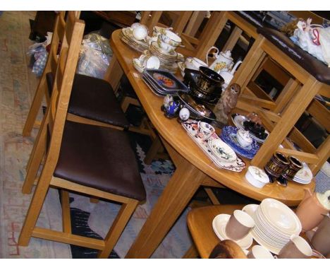 A light oak oval extending dining table - length 154cm closed, together with the set of eight ladder back dining chairs