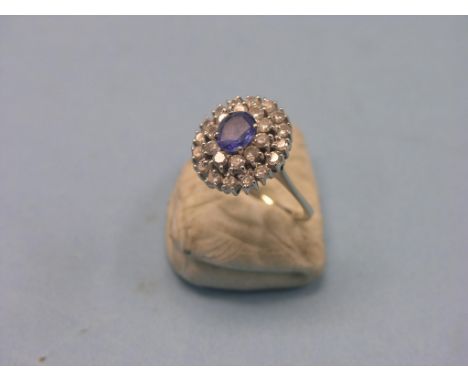 A sapphire and diamond cluster dress ring, stepped, oval form with numerous diamond chips surrounding central oval sapphire, 