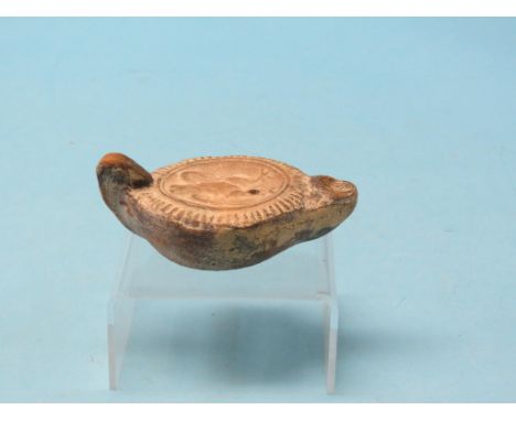 A Roman terracotta oil lamp, relief-cast with an imperial eagle, circa 43-400AD, 4.75in. long - discovered at Chichester, Wes