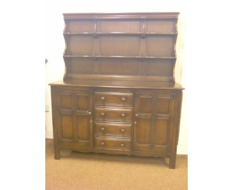 An Ercol dark elm dresser, twin-shelf plate rack above panelled cupboard base with four drawers, 4ft. 9in. wide, together wit