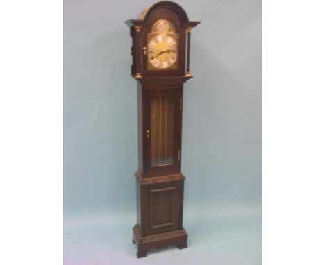 A reproduction mahogany longcase clock, featuring traditional arched brass dial and glazed trunk door, movement chiming on ei