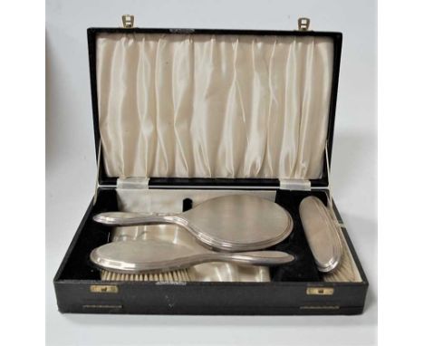 A cased engine turned silver backed three-piece dressing table set, comprising hairbrush, clothes brush, and hand mirrorCondi