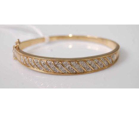 A modern yellow metal and diamond point set hinged bangle, arranged as pavé set diamond highlights in diagonal bands, unmarke