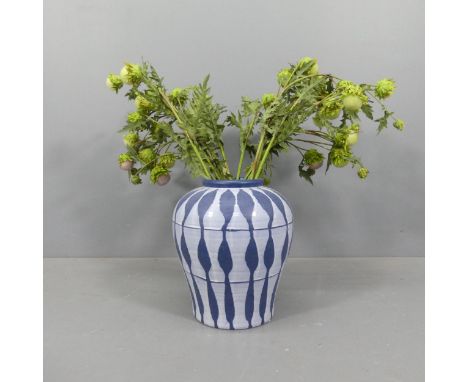 A large ceramic blue-ground studio vasem with white geometric design. 34x38cmArtificial flowers are included. 