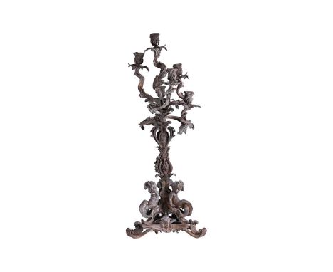 A large late 19th century patinated bronze candelabra, the six sconces on leaf scroll entwined arms, with three putti at the 
