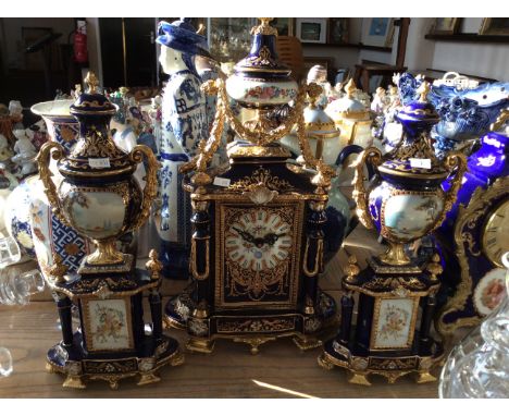 A blue floral and gilt mantle clock together with two matching decorative urns.