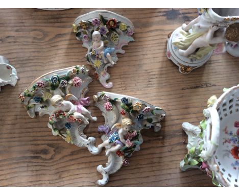 Three ceramic wall hanging with cherub figurines, gilded and flower detail.