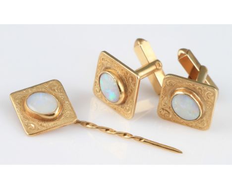 A pair of yellow metal opal cufflinks and tie pin, both cufflinks and tie pin of square design and set with a central oval op