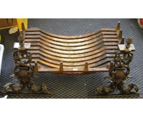 A cast iron fire grate with decorative detailing to front including Dragons, shield and topped with pineapple style finial.