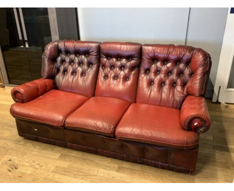 A three seater chesterfield sofa, upholstered in rouge red hide/leather, button back decoration. L165cm, H84cm.