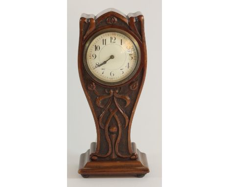 An Art Nouveau mantle clock with a carved overcoated mahogany case in a "Lyre form" enameled white dial and brass bezel, move