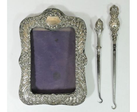 A silver embossed photograph frame, Birmingham 1906, 20 x 14cm and two silver button hooks (3) 