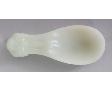 A CHINESE PALE CELADON JADE SPOON, its handle modelled in the form of the head of Shou Lao, 4.2in long.