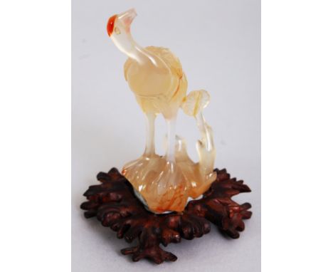 A CHINESE GREY AGATE MODEL OF A STANDING STORK, together with a shaped and carved wood stand, the stone with russet inclusion