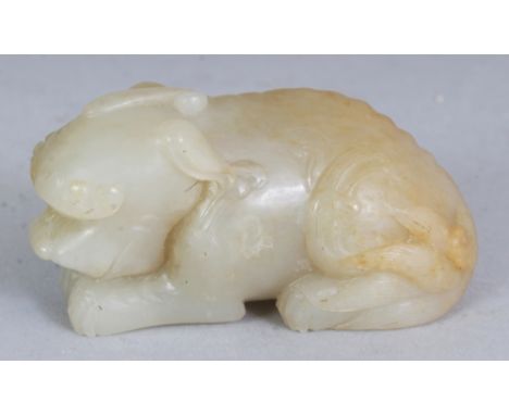 A GOOD QUALITY CHINESE CELADON JADE MODEL OF A CROUCHING BUDDHISTIC LION, the stone with russet inclusions, 2.7in long & 1.4i