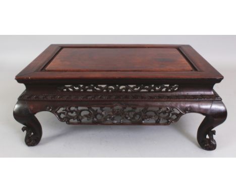 A 19TH CENTURY CHINESE CARVED HARDWOOD RECTANGULAR STAND, supported on floral scroll feet, the pierced frieze decorated with 