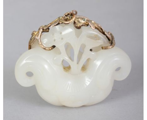 A CHINESE WHITE JADE PENDANT, with a gilt metal clasp, the stone carved with a pierced mask and floral design, 2in wide & 1.6