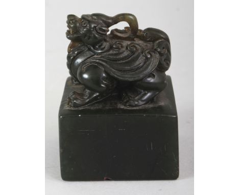 A CHINESE GREEN JADE-LIKE SOAPSTONE SEAL, of square section and surmounted by a mythical animal, 2.3in square & 3.1in high.