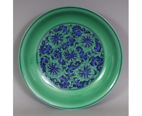 A CHINESE GREEN GROUND UNDERGLAZE-BLUE PORCELAIN SAUCER DISH, the interior centre and exterior sides decorated with a formal 