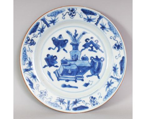 A CHINESE KANGXI PERIOD BLUE & WHITE PORCELAIN PLATE, painted to its centre with scholar's objects and ribboned emblems, 8.75