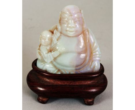 A GOOD QUALITY CHINESE OPAL-LIKE HARDSTONE CARVING OF BUDAI, together with a fitted wood stand, the deity in the company of a
