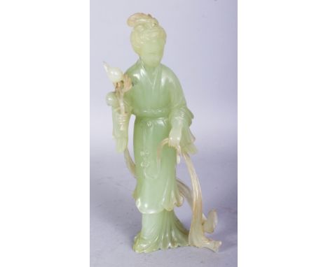 A CHINESE CELADON GREEN JADE FIGURE OF GUANYIN, standing and bearing a sprig of peach, 8.5in high.